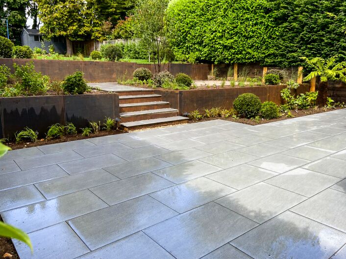 Contemporary landscaped garden in Cobham with corten steel retaining walls and stone paving